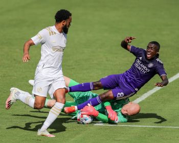 Orlando City SC midfielder JHEGSON SEBASTIAN MENDEZ (8) trips over Atlanta United goalkeeper BRAD GUZAN (1) while diving for a save during the Orlando City vs Atlanta United match at Exploria Stadium in Orlando, Fl on April 17, 2021.